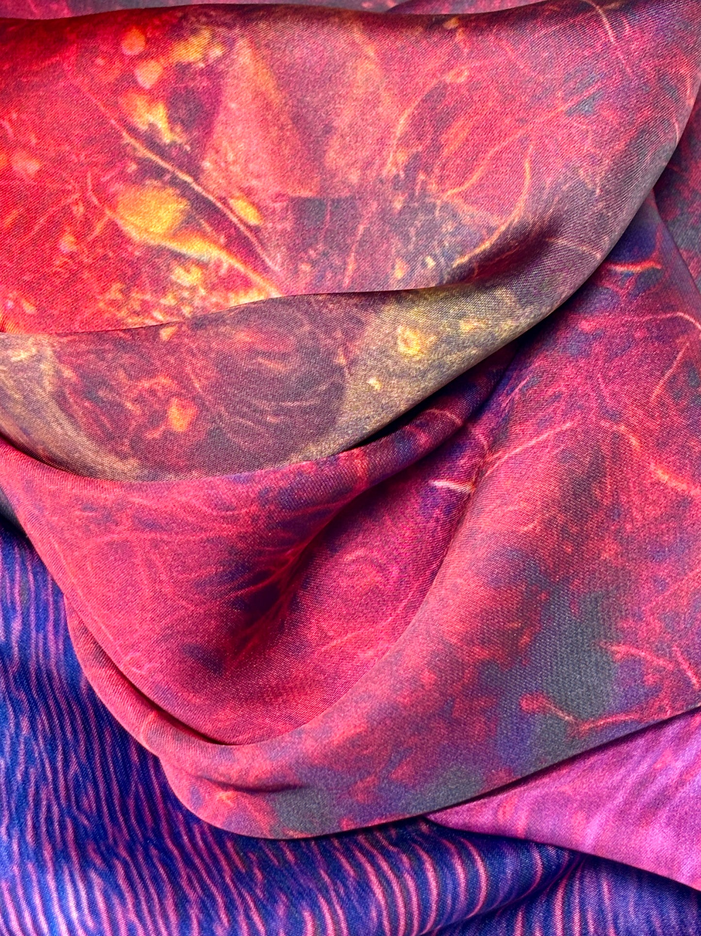 Close up of Rhododendron satin scarf showing patterns of red, yellow ,blue and pink.