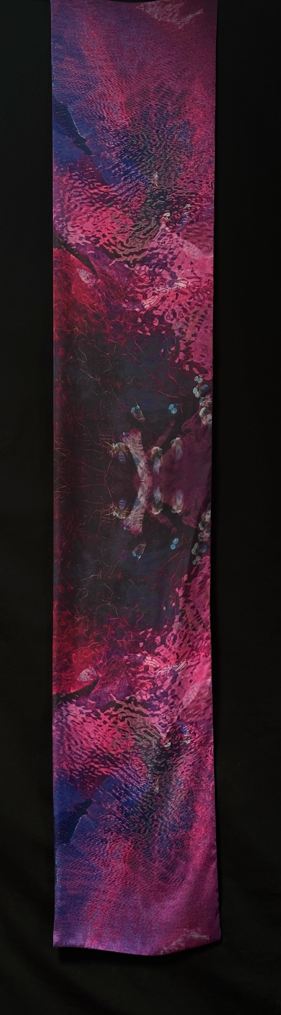 Back of scarf approximately 185cm x 33 cm. Colours are pinks, purples and black with water ripples and seaweed patterns.
