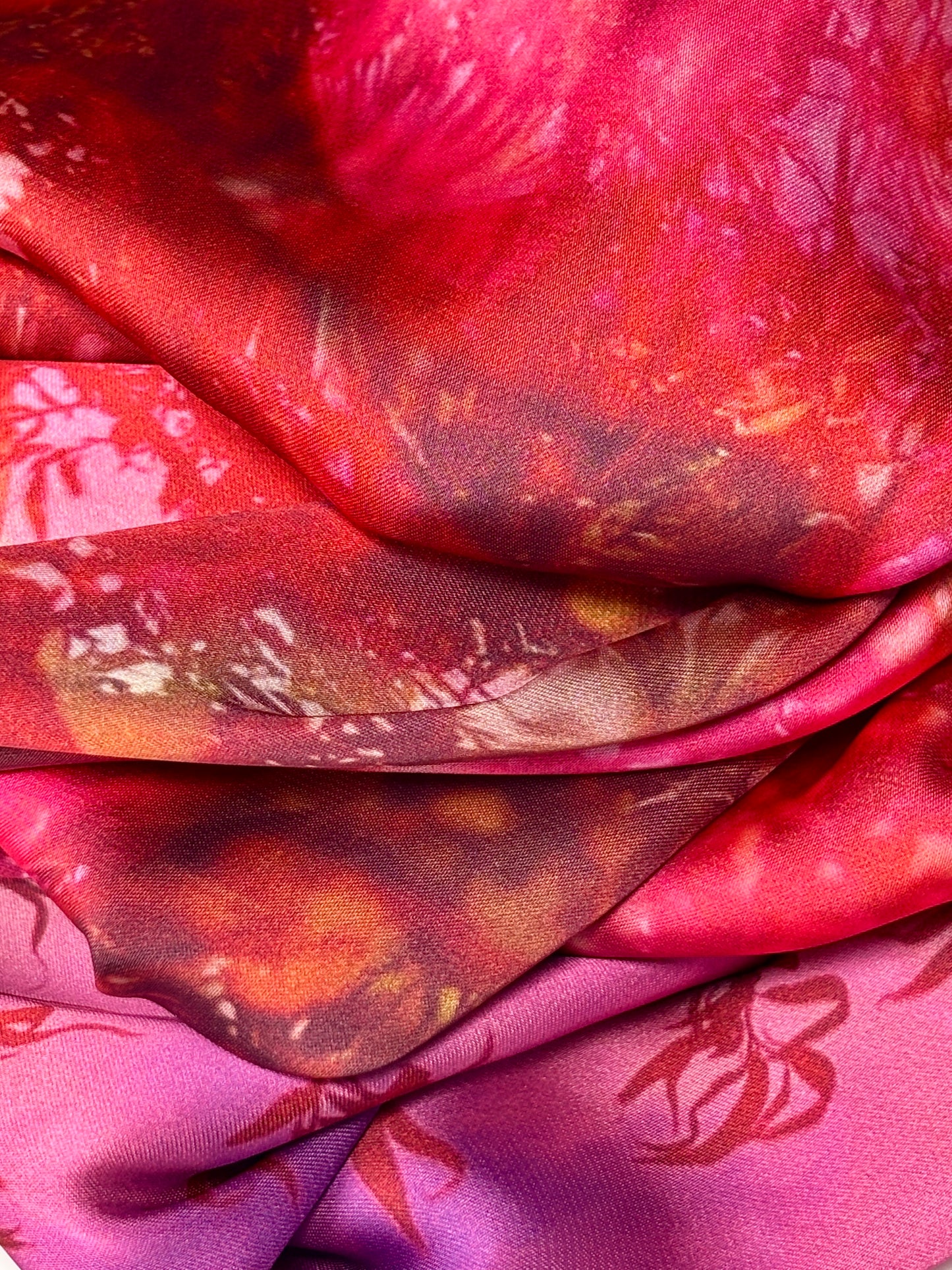 Close up of fabric showing patterns on red, yellow pink and purple fabric.